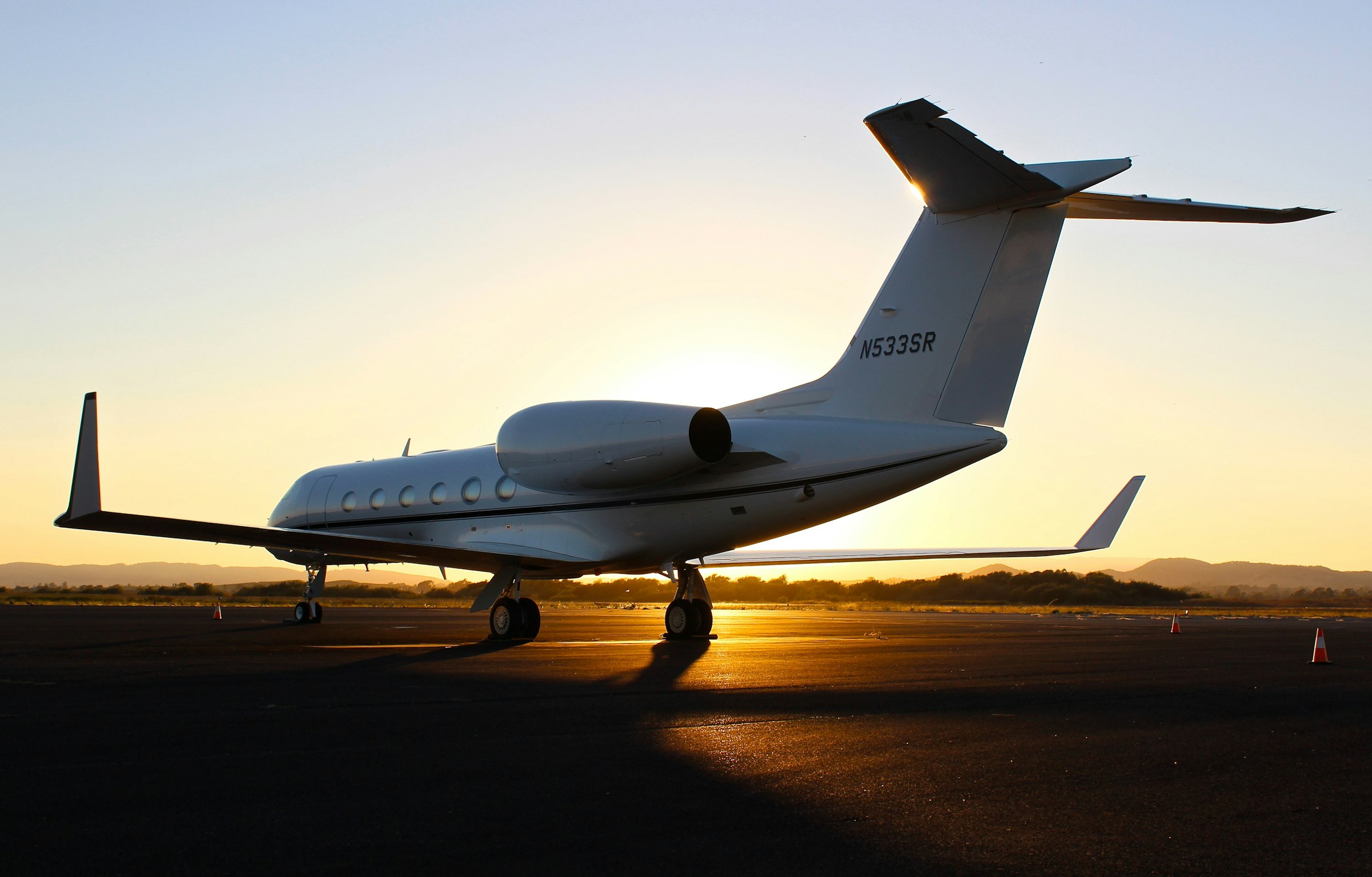 Private jet silhouetted against a golden sunset on the tarmac